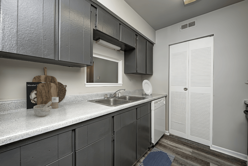 an empty kitchen with gray cabinets and a stainless steel sink