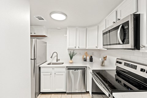 a white kitchen with stainless steel appliances and white cabinets at Merrick Place, Lexington, KY