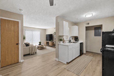 A kitchen with white cabinets and a black fridge is shown.