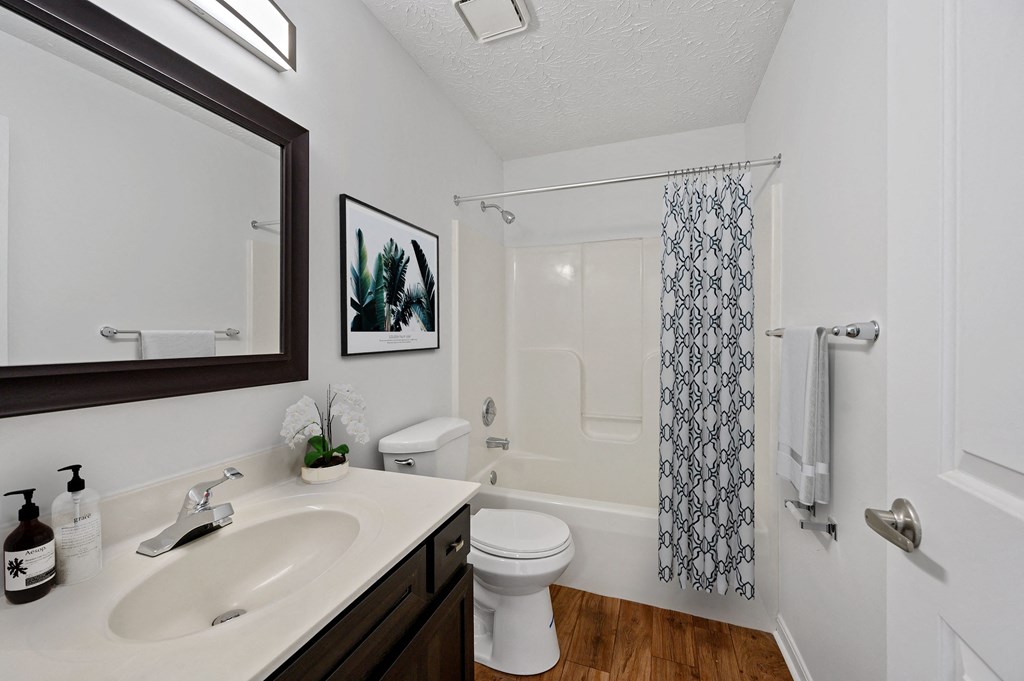 a bathroom with a white toilet and a black and white shower curtain