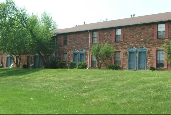 a large brick building with blue doors and a grassy yard
