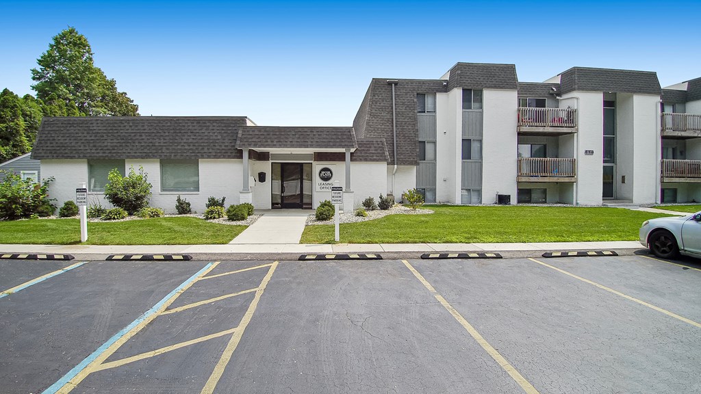 a parking lot in front of a large white building with a gray roof