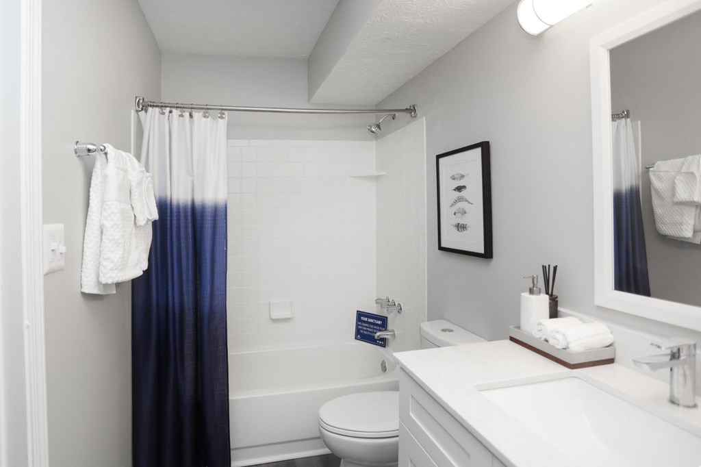 A white bathroom with a toilet, sink, and shower.at Spinnaker Court, Indianapolis, IN 46214