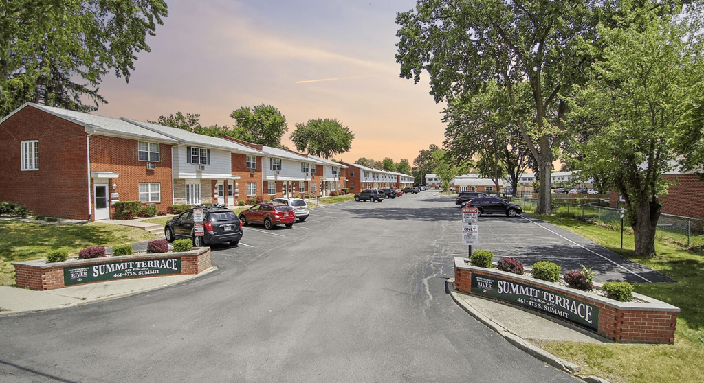 a street with houses and cars parked in a parking lot