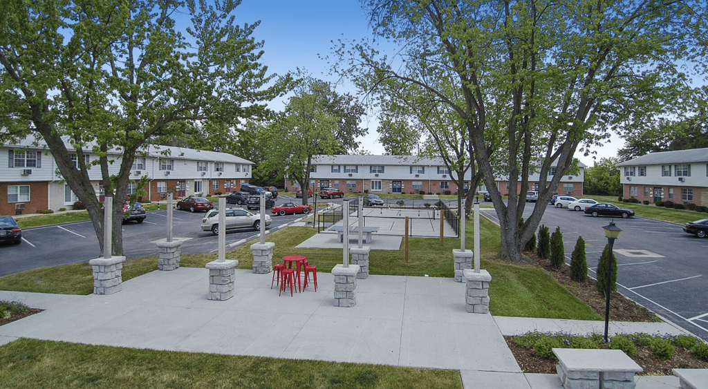a park area with tables and chairs in front of a parking lot