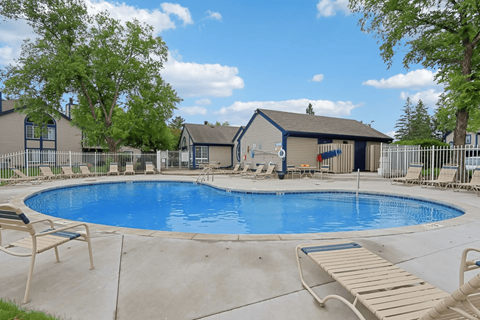 A small pool with a deck and a house in the background.