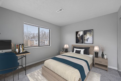 A bedroom with a bed, nightstand, and chair at The Reserve at Grand Valley Apartments, Milford