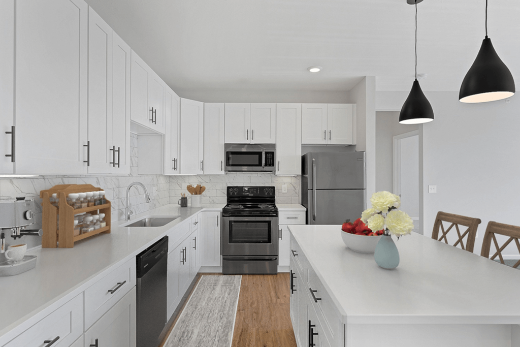 a large white kitchen with stainless steel appliances and white cabinets at Monmouth Row Apartments, Newport, KY