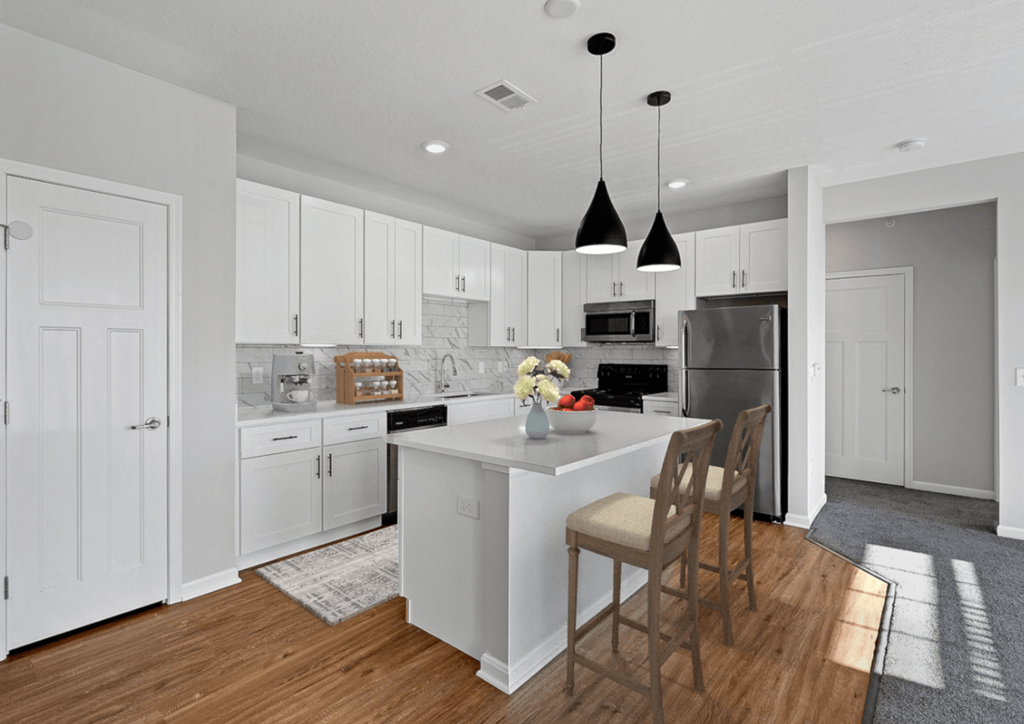 a kitchen with white cabinets and a white island with chairs at Monmouth Row Apartments, Newport, 41071