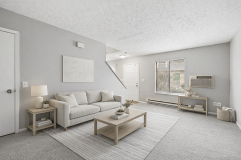 A living room with a grey couch, a coffee table, and a painting on the wall.