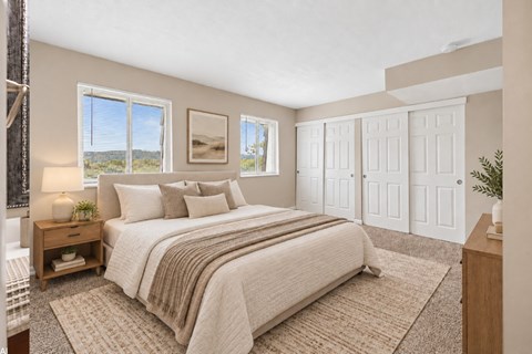 A bedroom with a large bed and a view of the outdoors through the window.