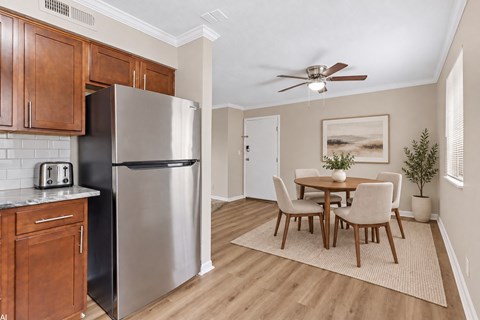 A kitchen with a refrigerator, toaster, and wooden cabinets.