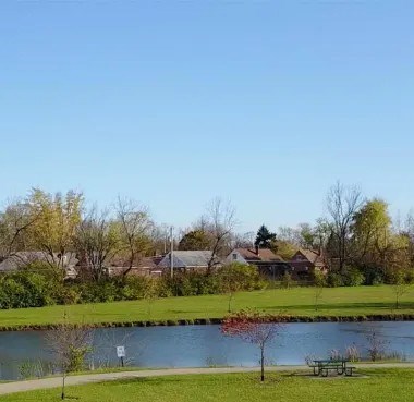 A serene park with a lake, trees, and a bench.