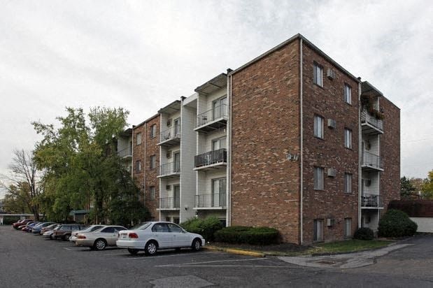 an apartment building with cars parked in a parking lot