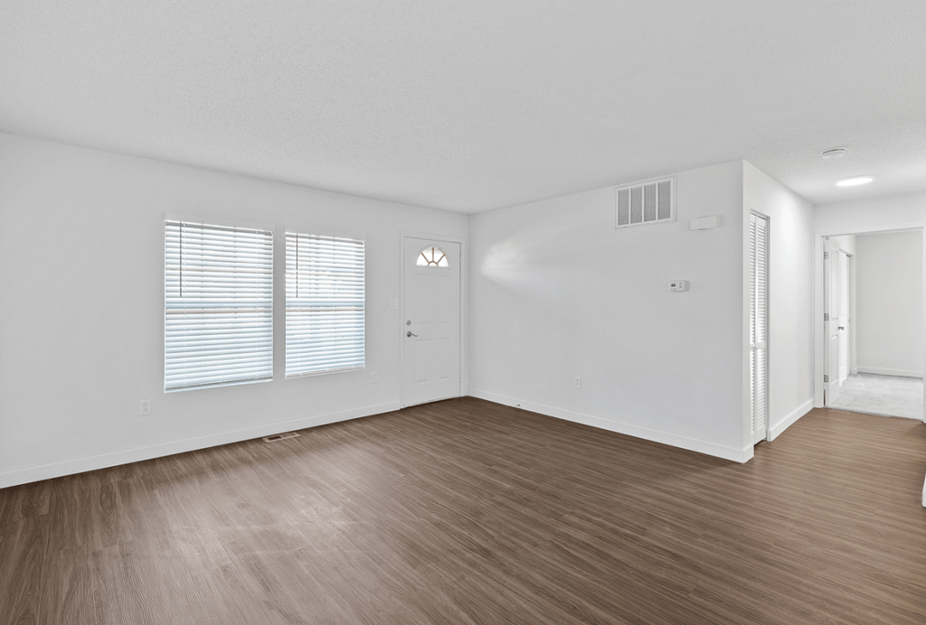 an empty living room with wood flooring and white walls