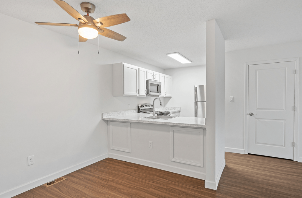 an open living room with a kitchen and a ceiling fan
