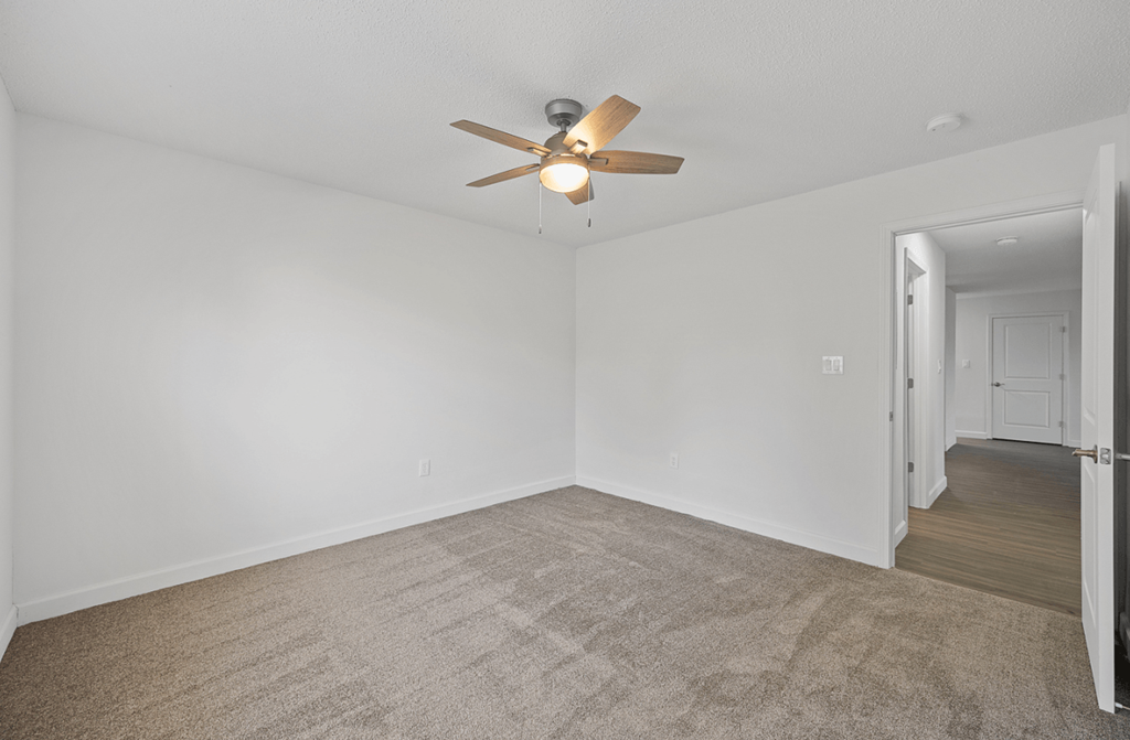an empty living room with white walls and a ceiling fan