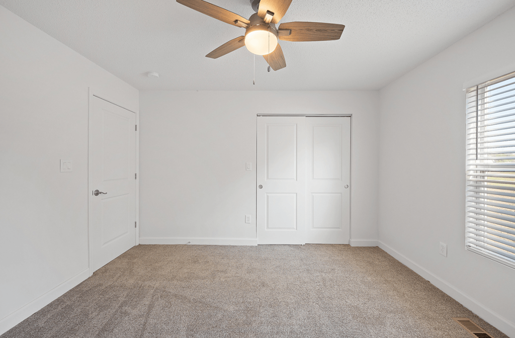 an empty living room with a ceiling fan and a door