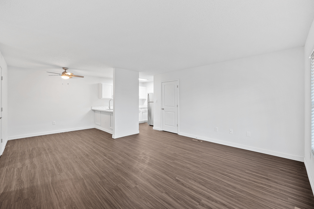 an empty living room with wood flooring and a ceiling fan