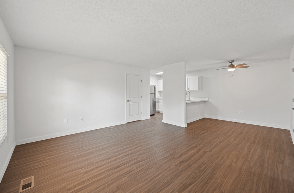 an empty living room with wood flooring and a ceiling fan