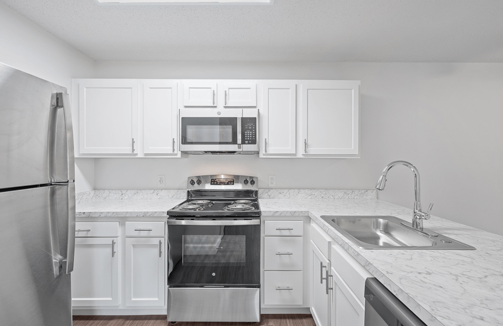 an empty kitchen with white cabinets and stainless steel appliances