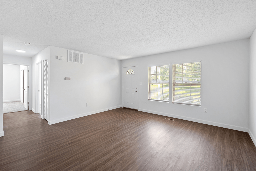 an empty living room with wood floors and white walls