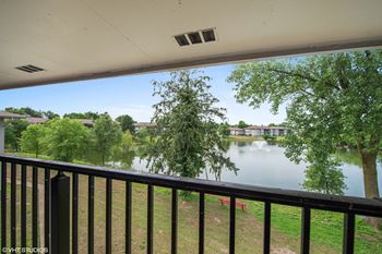 A balcony overlooks a body of water with trees in the background.