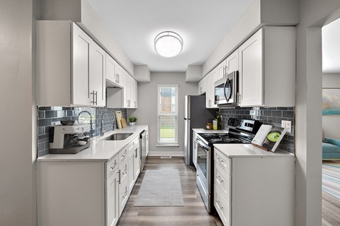 A modern kitchen with white cabinets and appliances.