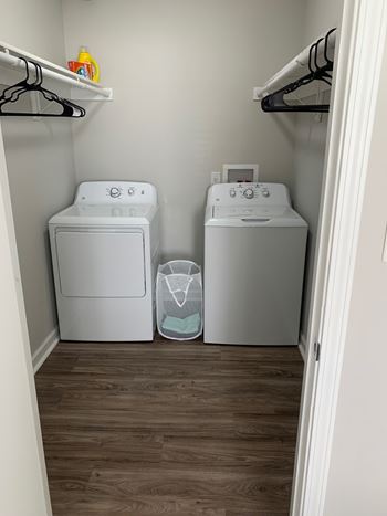 A small laundry room with two washing machines and a shelf above them.