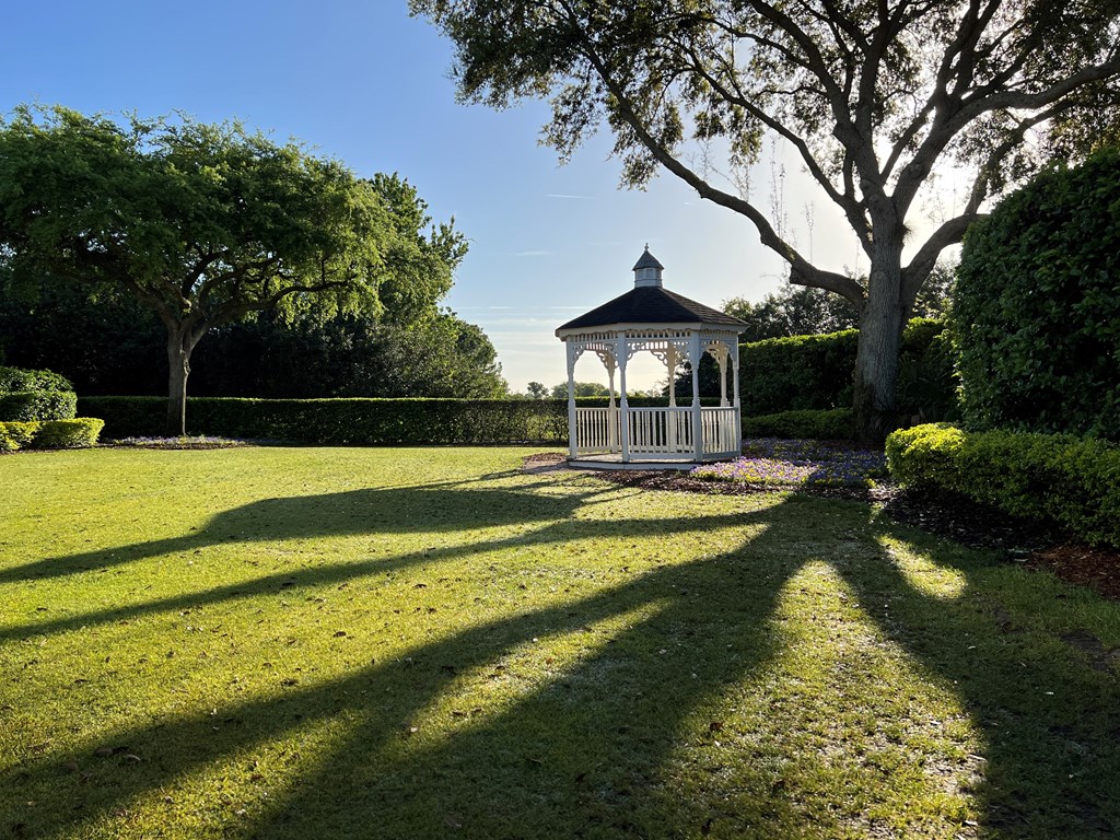 A gazebo is in the middle of a grassy field.