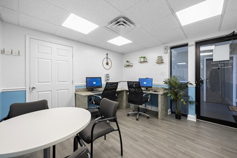 A room with a white table and chairs, a white door, and a window with blinds.