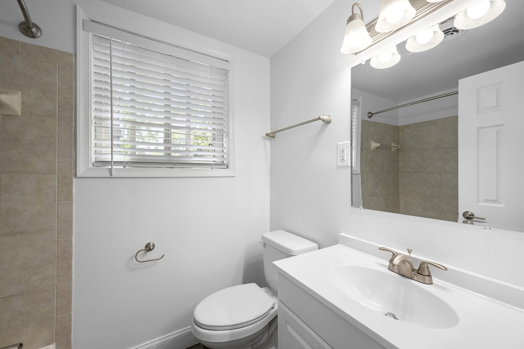 A white bathroom with a toilet, sink, and shower. at Bren Mar Apartments, Alexandria, Virginia