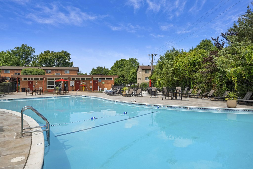 A large outdoor swimming pool surrounded by trees and lounge chairs at Rose Hill Apartments, Virginia