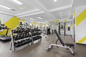 A gym with a variety of equipment including weights and a bench at Rose Hill Apartments, Virginia