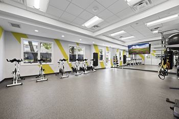 A gym with exercise bikes and a television screen at Rose Hill Apartments, Alexandria