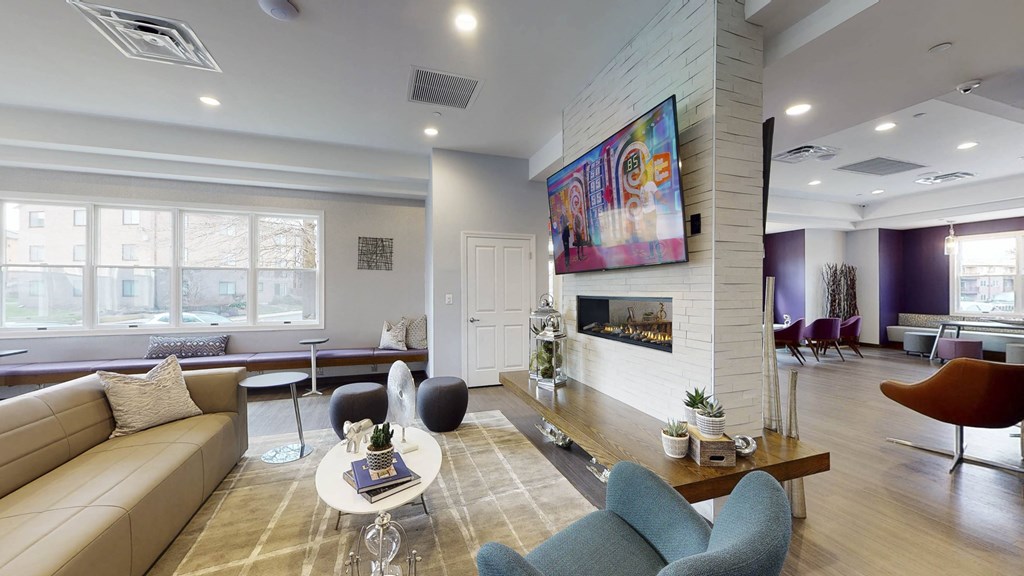 A living room with a tan couch, a blue chair, and a painting on the wall at Rose Hill Apartments, Alexandria, VA, 22310