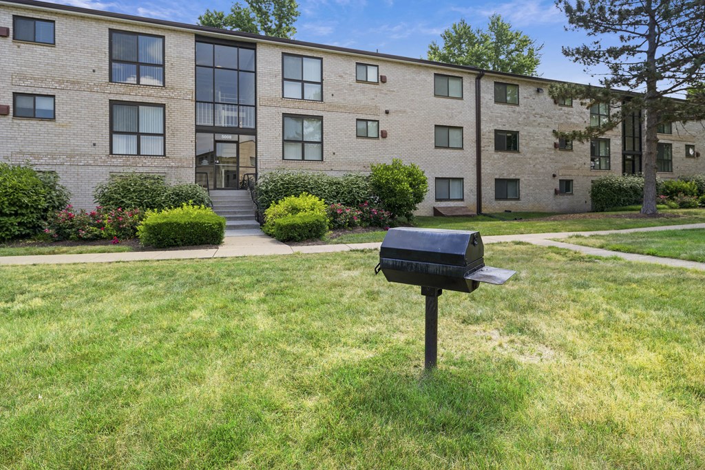 A black mailbox sits on a green lawn in front of a brick building at Rose Hill Apartments, Alexandria