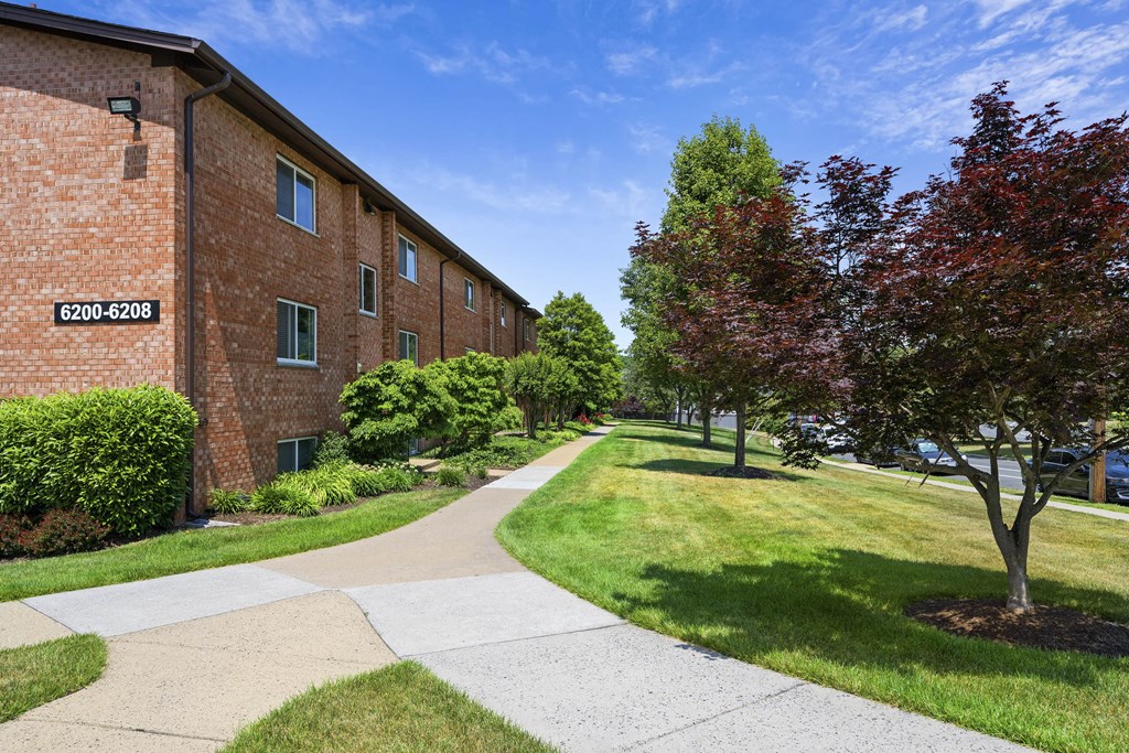 A building with the number 6200-6208 on it is surrounded by greenery and a paved walkway at Rose Hill Apartments, Virginia, 22310