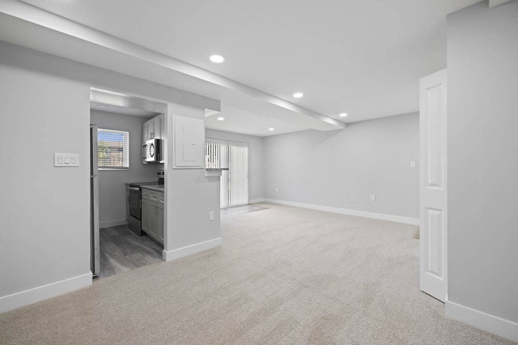 A spacious, empty room with a kitchen area visible through the open door at Rose Hill Apartments, Virginia, 22310