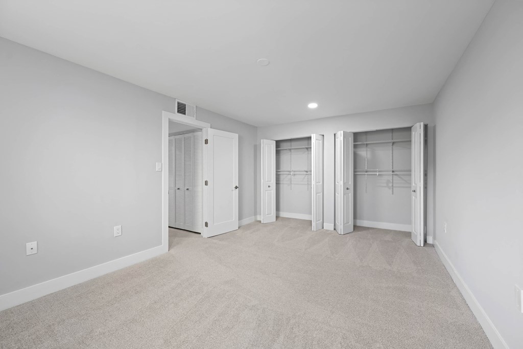 A room with white walls and carpeted floor with a white door on the left at Rose Hill Apartments, Virginia