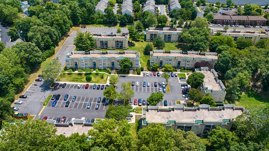 an aerial view of a parking lot with several buildings and trees at Stuart Woods* Apartments, Virginia