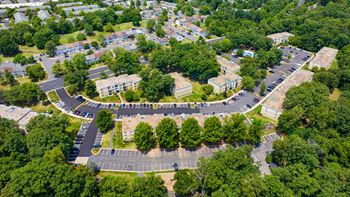 an aerial view of a parking lot with trees and buildings at Stuart Woods* Apartments, Virginia
