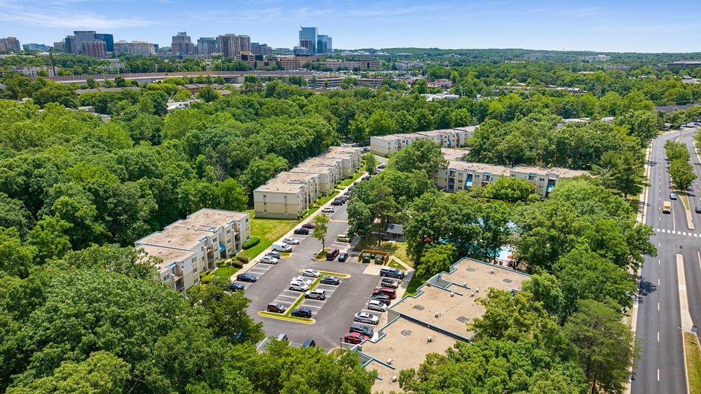 an aerial view of an apartment complex with trees and a city in the background at Stuart Woods* Apartments, Herndon, 20170