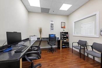 an office with a desk with a computer and chairs