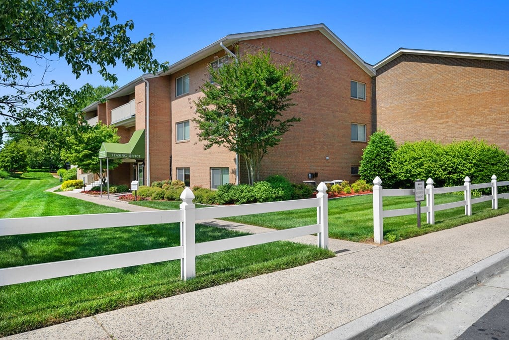 a white fence in front of a brick building at Gainsborough Court Apartments, Virginia