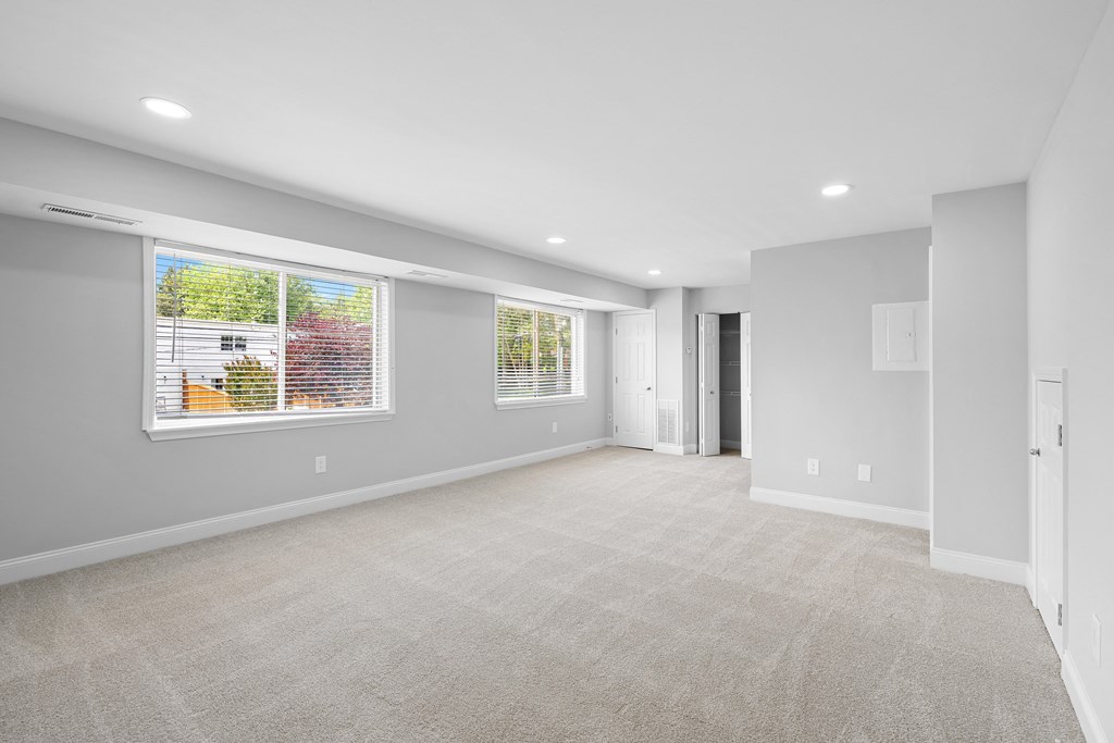 an empty living room with a large window and a door at Gainsborough Court Apartments, Fairfax, 22030
