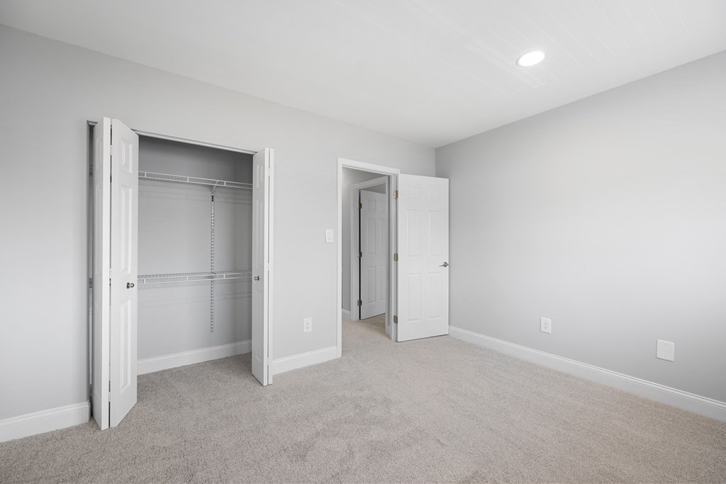 an empty bedroom with white closets and a carpeted floor at Gainsborough Court Apartments, Fairfax, VA, 22030