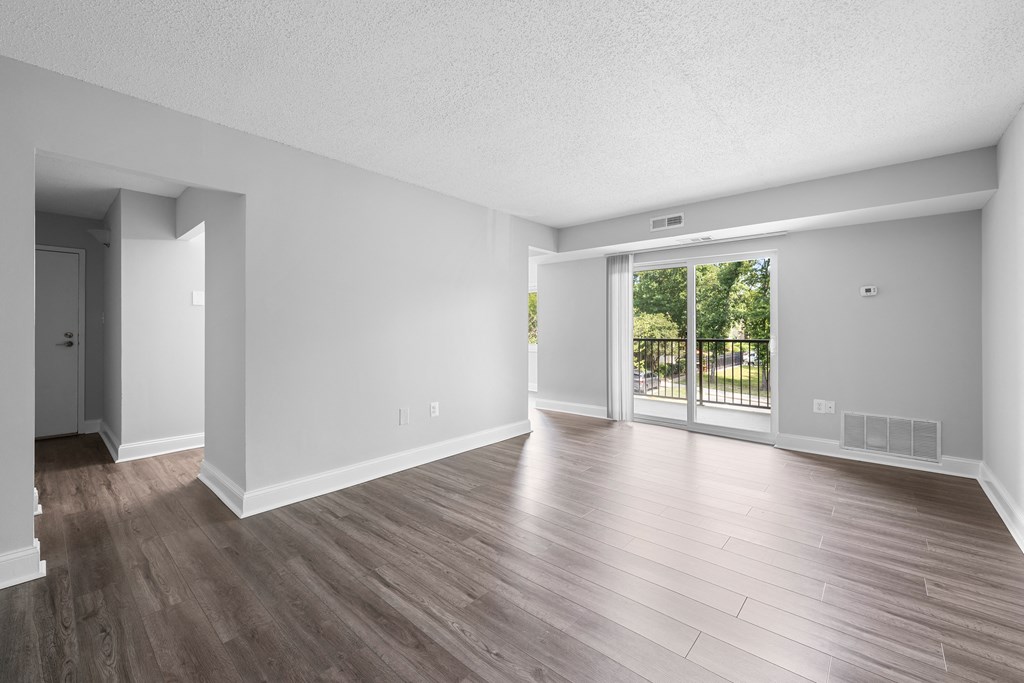 the living room of an empty apartment with wood flooring and a sliding glass door at Stuart Woods* Apartments, Virginia, 20170