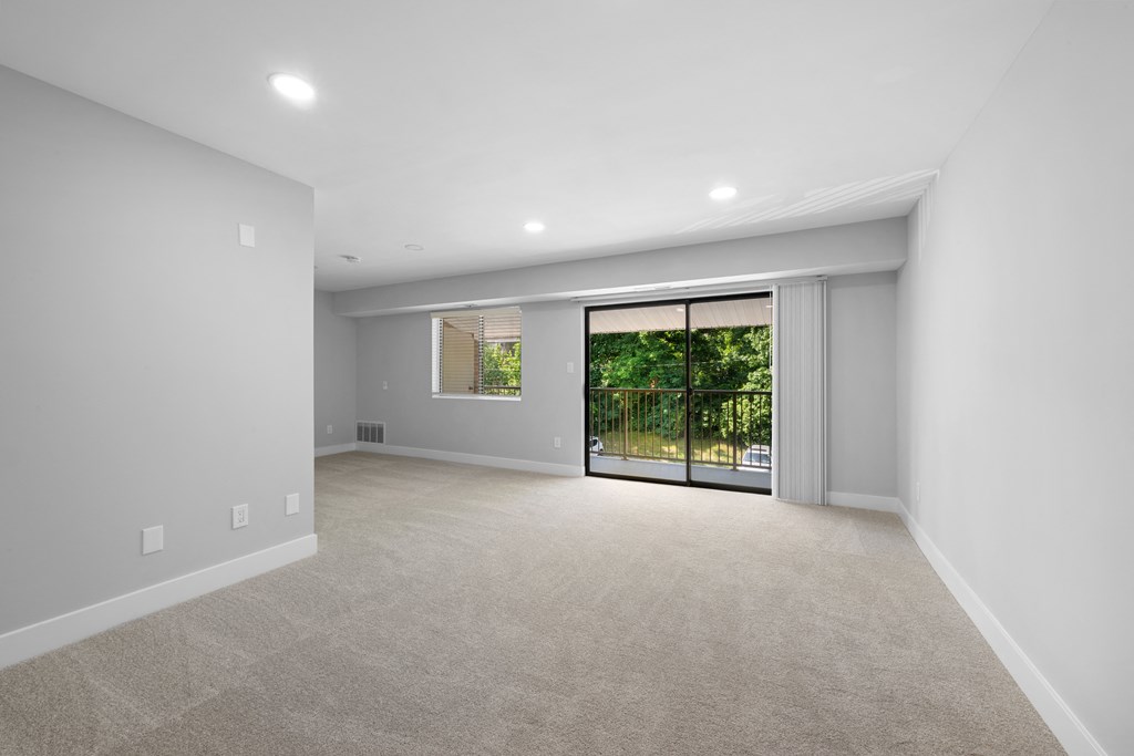 a living room with white walls and a door to a balcony at Gainsborough Court Apartments, Fairfax, 22030