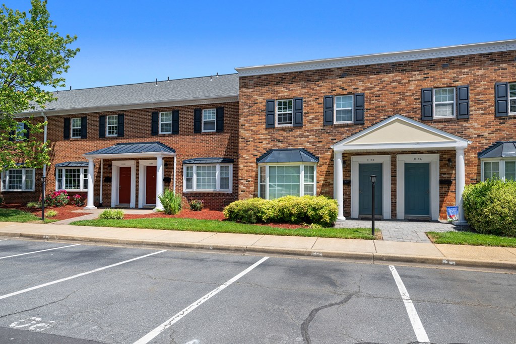 a red brick building with blue doors and a parking lot at Gainsborough Court Apartments, Fairfax, VA, 22030